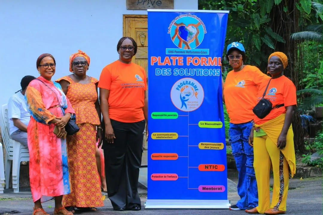 Des mamans et des membres de l'ONG réunies devant la bannière Plate-forme des Solutions